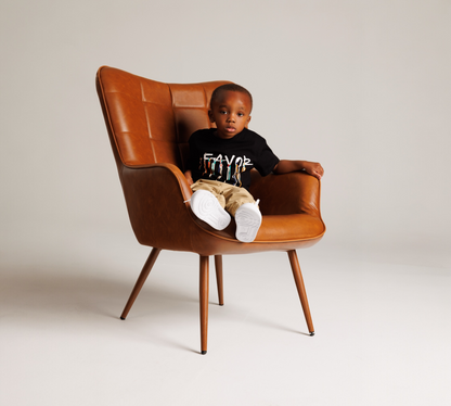 Child sitting in a brown leather chair against a plain background